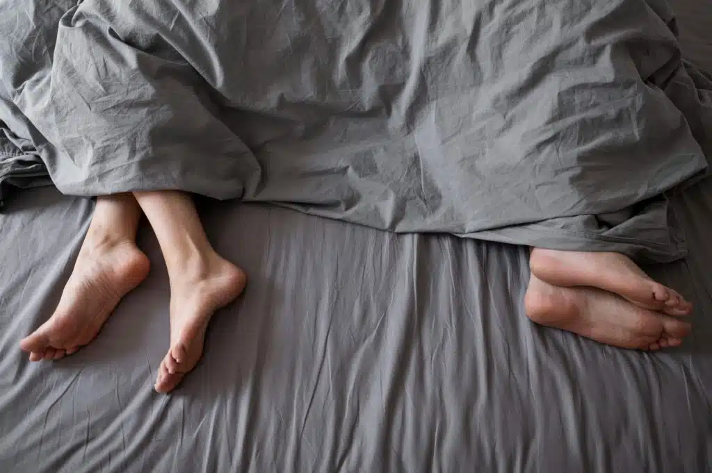 Cama de casal com duas pessoas dormindo afastadas