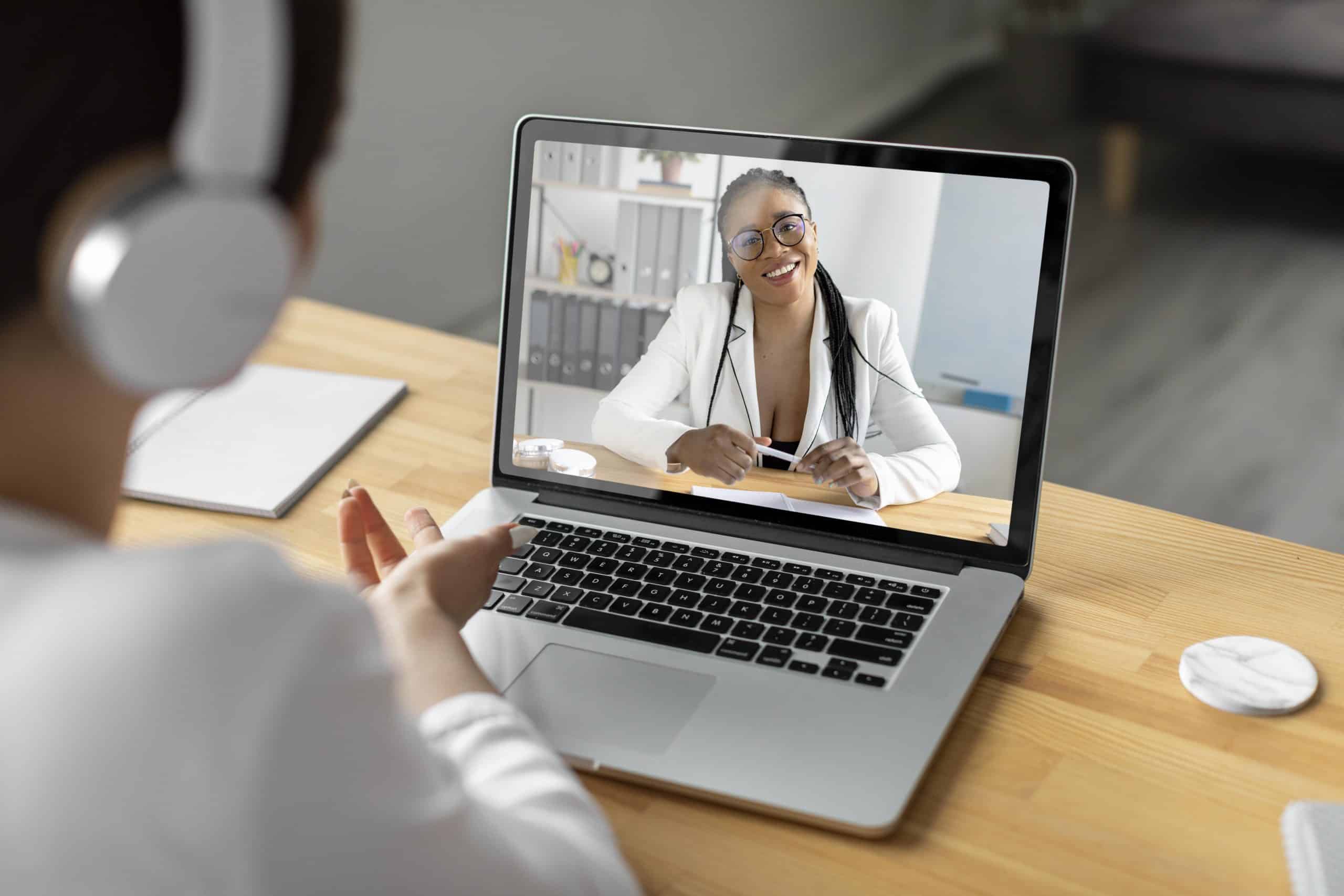Paciente em consulta por telemedicina, conversando com uma profissional de saúde por vídeo chamada no notebook, ilustrando o uso da saúde digital e do atendimento médico remoto