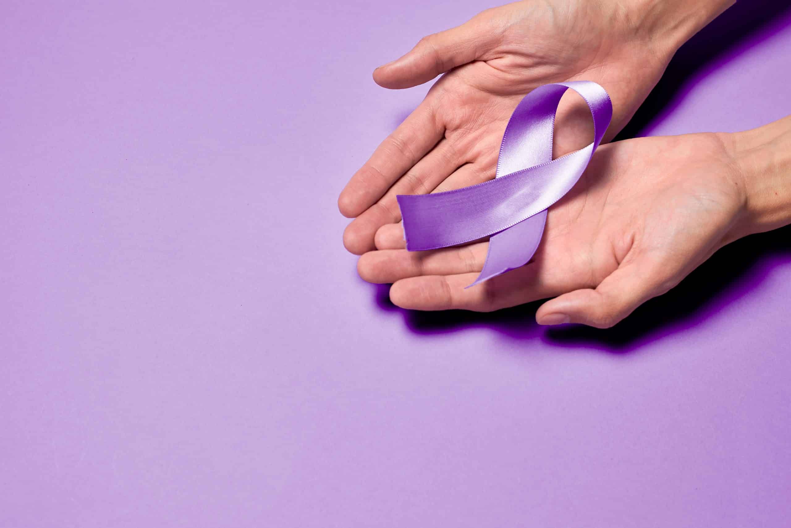 Mãos segurando um laço roxo em campanha de conscientização da hanseníase