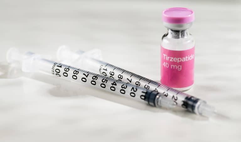 Frasco de tirzepatida 40 mg ao lado de seringas graduadas, sobre fundo claro, representando medicamento injetável de uso controlado.