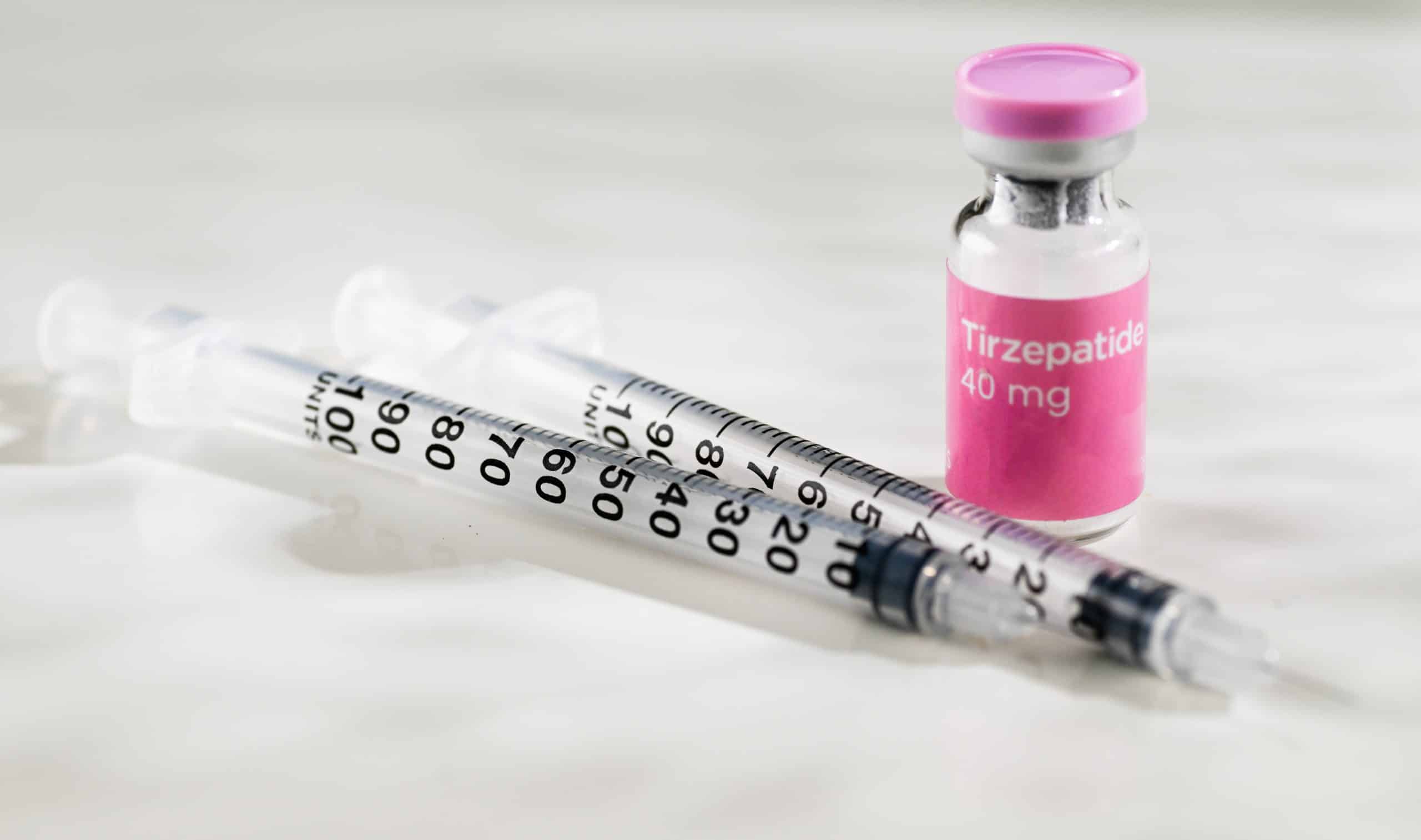 Frasco de tirzepatida 40 mg ao lado de seringas graduadas, sobre fundo claro, representando medicamento injetável de uso controlado.