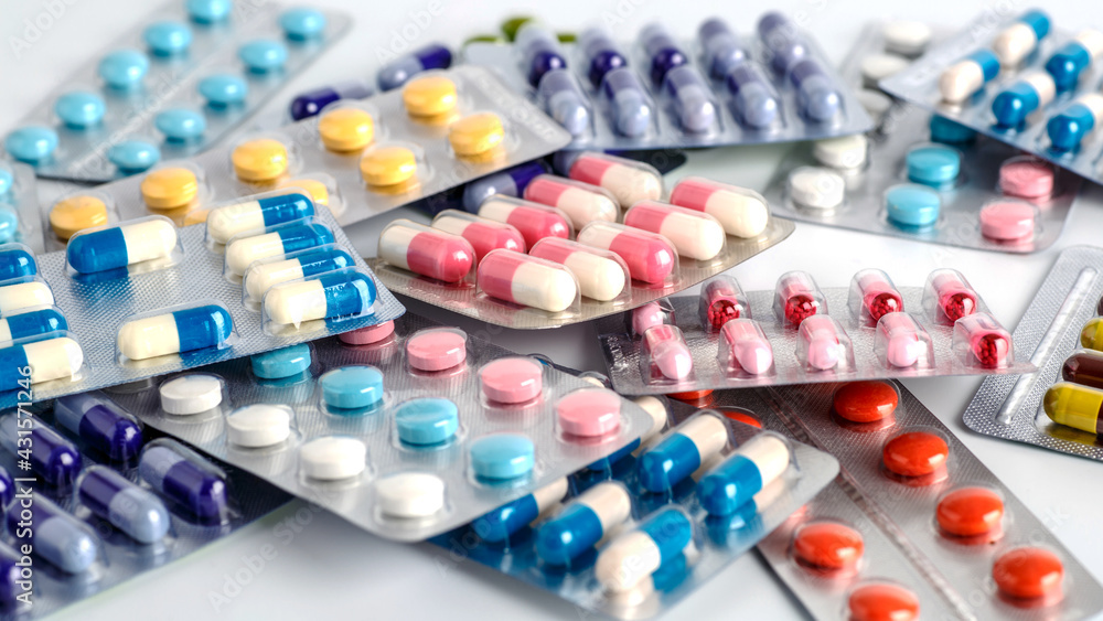 Cartelas com diferentes comprimidos e cápsulas coloridas organizadas sobre a mesa, representando medicamentos utilizados no tratamento de Doença Crônica.