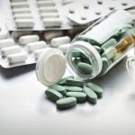 Frascos abertos e cartelas com comprimidos e cápsulas sobre a mesa, ilustrando diferentes formas de uso de medicamentos, incluindo medicamento sublingual e via oral.