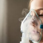 Criança utilizando máscara de nebulização, procedimento que ajuda a aliviar sintomas respiratórios e facilitar a respiração em casos de doenças das vias aéreas.